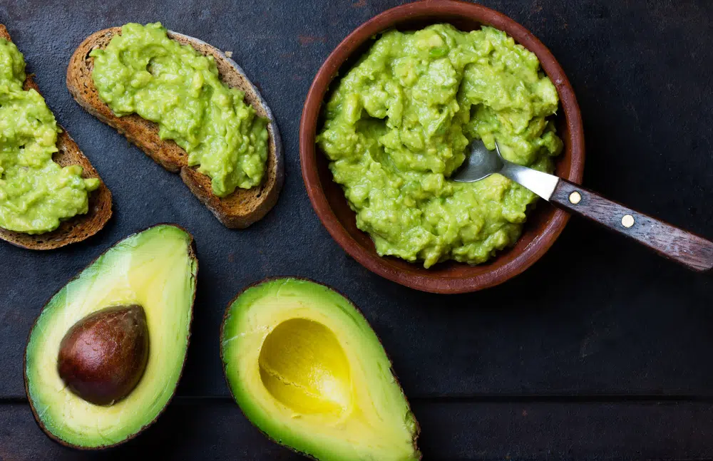 Avocado Cut In Half, Guacamole In A Bowl And Avocado Toasts