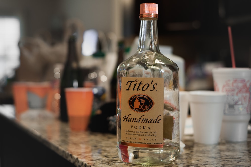 Glass Bottle Of Tito's Handmade Vodka Sitting On Top Of A Bar Counter