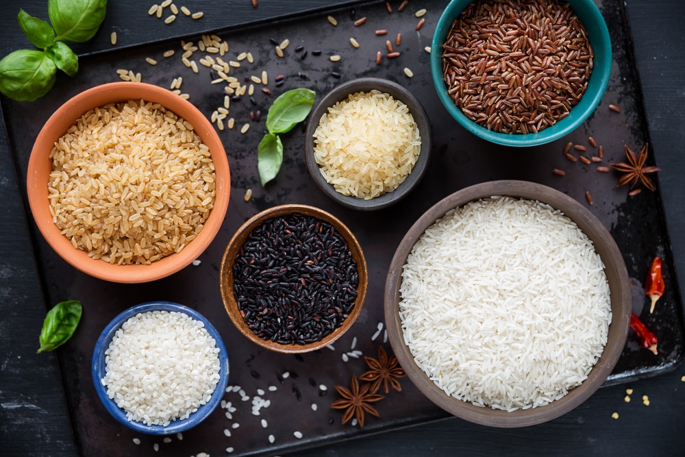 Verschillende soorten rijst in kommen - rood, zwart, basmati, volkoren, langkorrelig voorgekookt en arborio