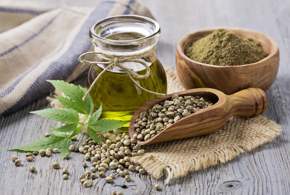 Hemp Oil, Hemp Seeds And Hemp Powder On A Wooden Table