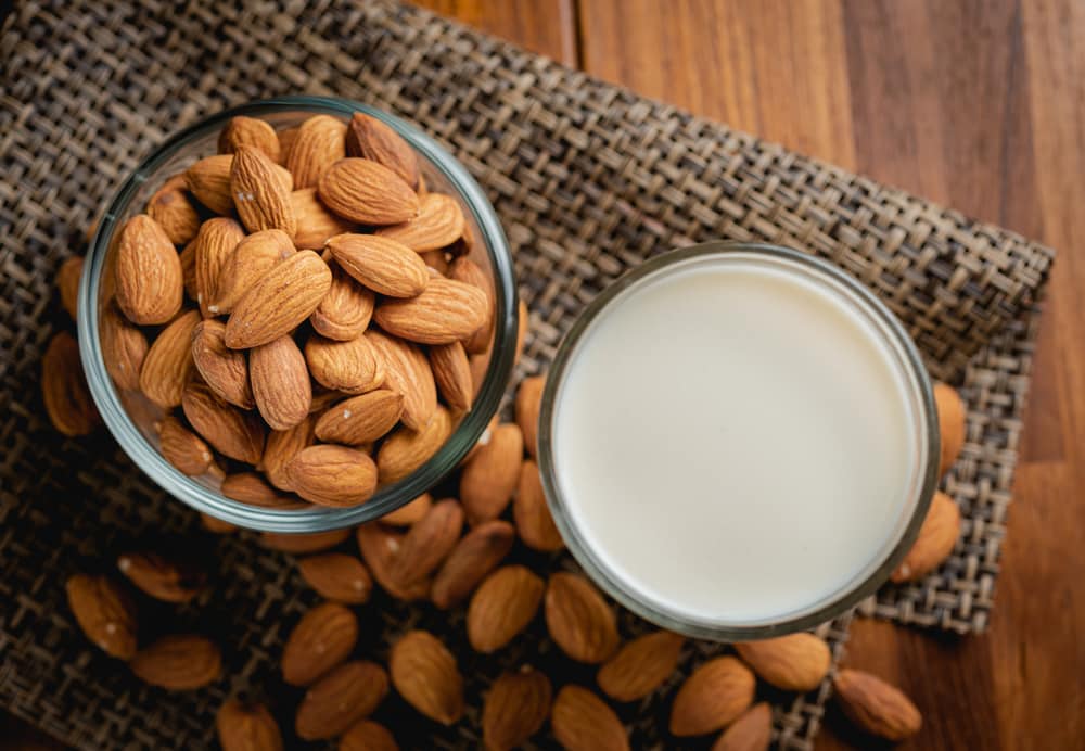 A Glass Of Almonds And A Glass Of Almond Milk On A Wooden Table