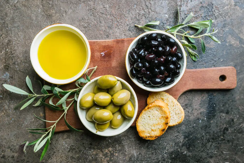 A Set Of Green And Black Olives And Olive Oil On A Dark Stone Background