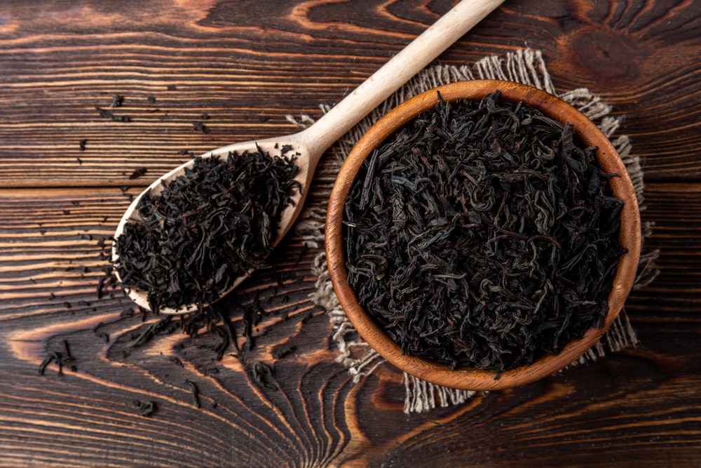 چای سیاه روی قاشق چوبی و کاسه چوبی