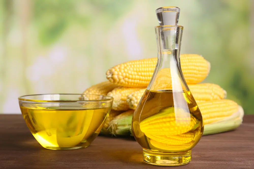 Corn Oil In A Bottle And Bowl With Corn Cobs In The Background