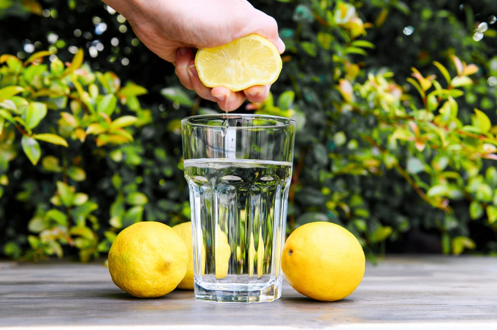 Hand Squeezing A Lemon Into The Water