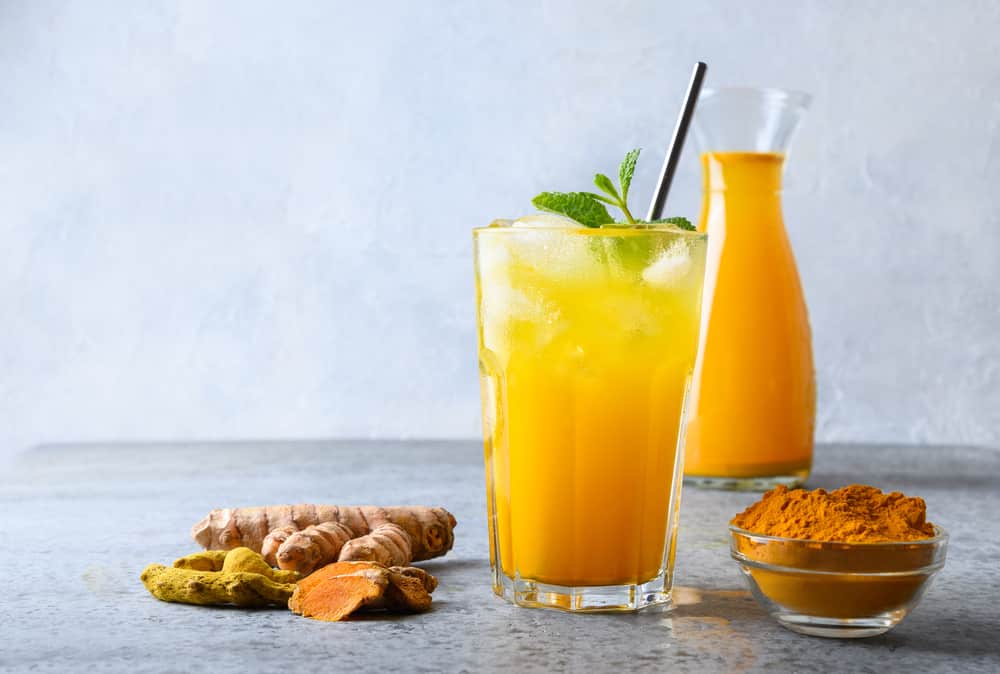 Iced Turmeric With Fresh Mint Leaves And Turmeric On Each Side Of The Drink