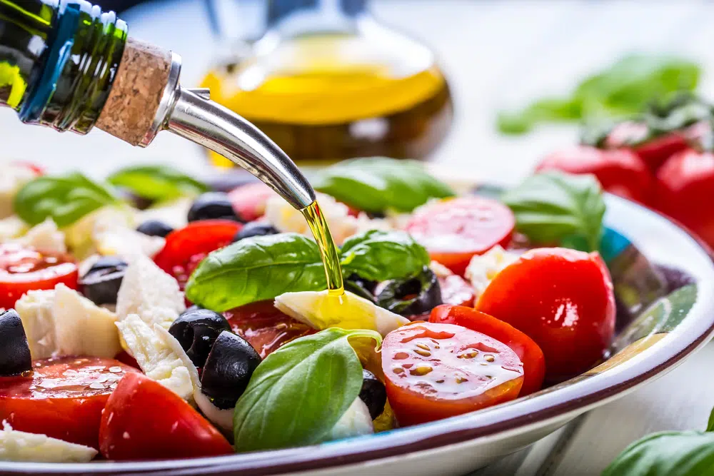 Olive Oil Being Poured On A Caprese Salad