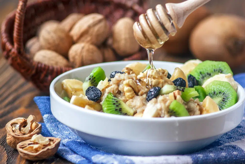 Organic Oatmeal With Fruits And Honey On A White Bowl