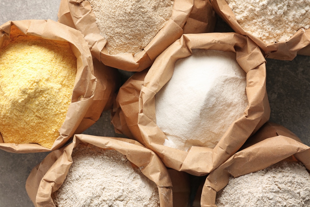 Paper Bags With Different Types Of Flour On Gray Background