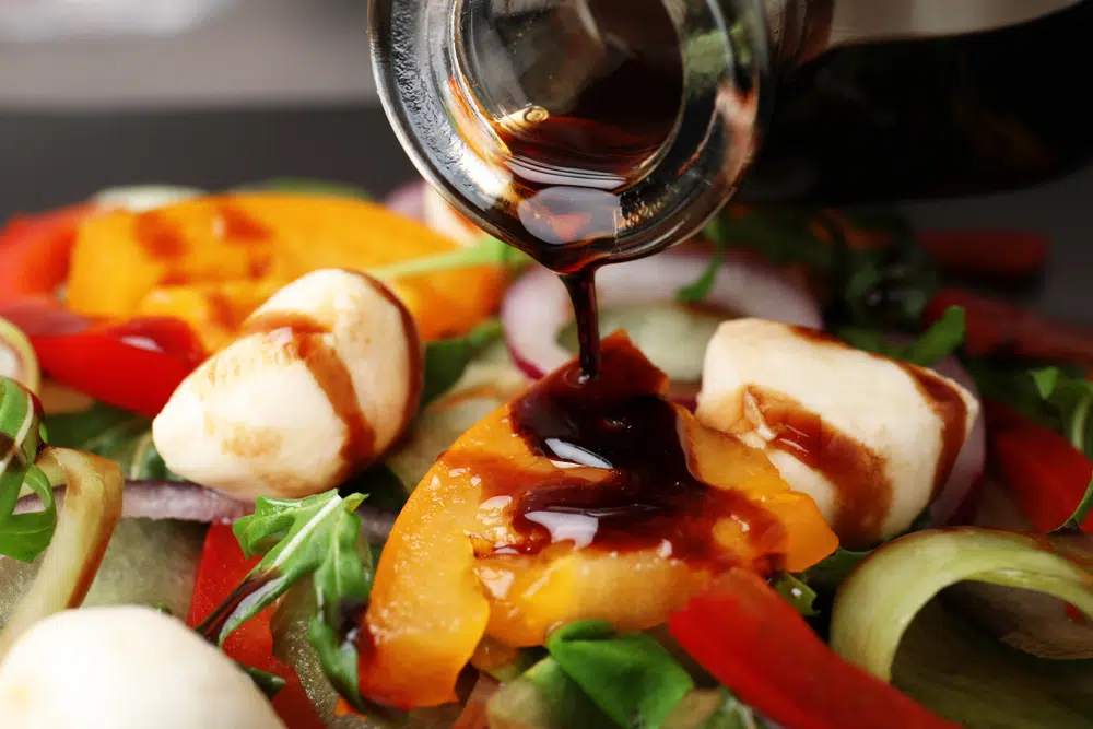 Pouring Balsamic Vinegar Onto Vegetable Salad