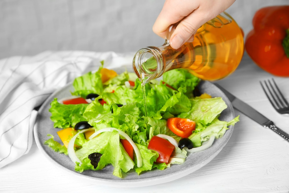 Woman Adding Apple Vinegar Into Salad On Plate