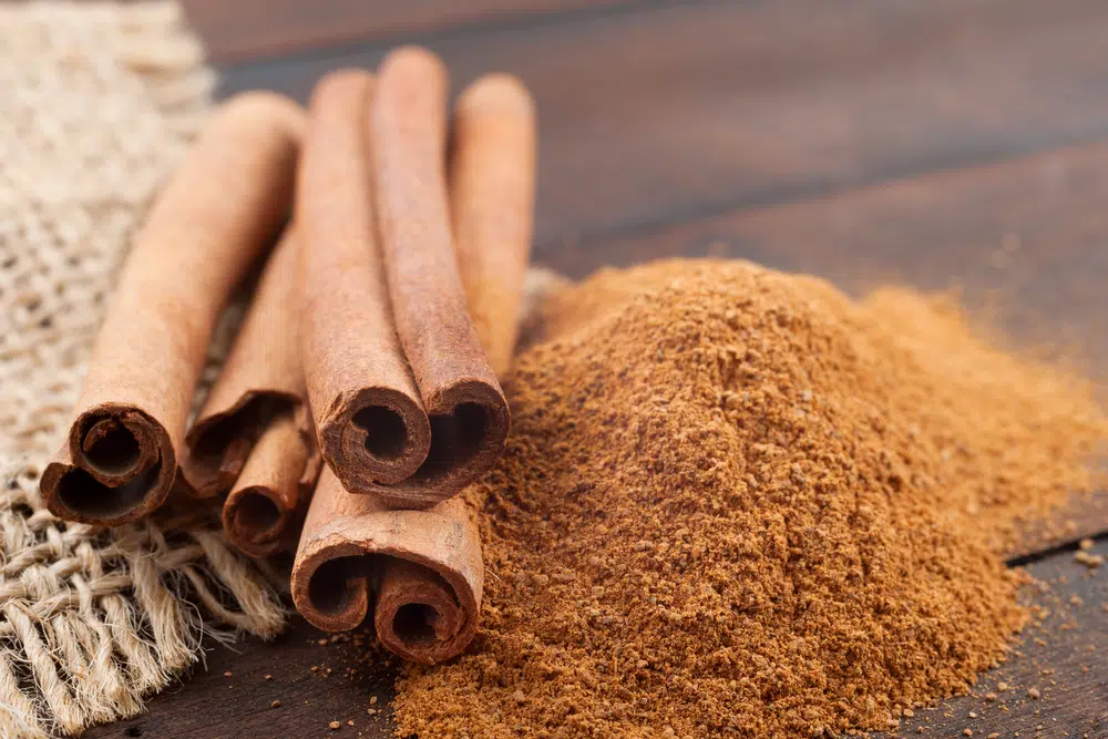 Cinnamon Sticks And Cinnamon Powder On Brown Wooden Board