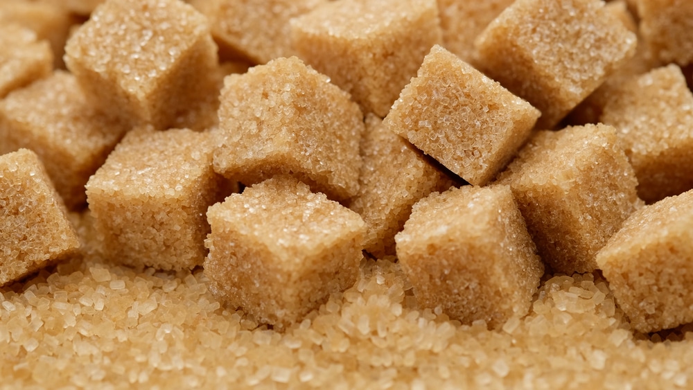 Een close-up van bruine suikerklontjes over suiker